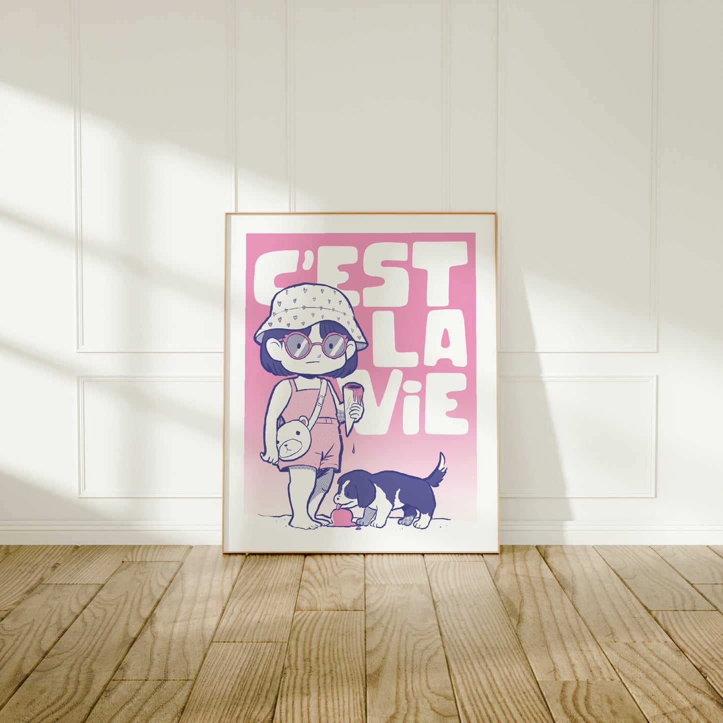 Large frame of the C'est La Vie poster leaning against a wall on a wooden floor 