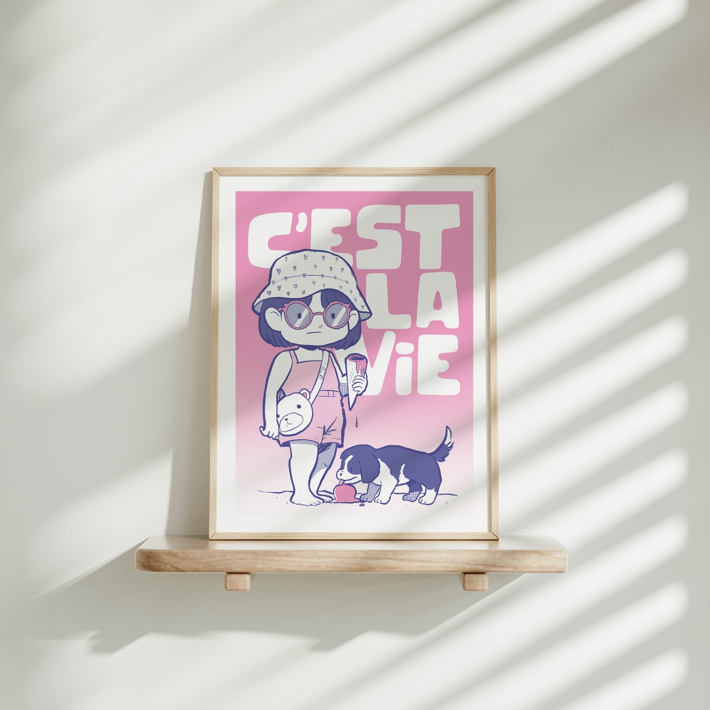 Medium frame of the C'est La Vie poster on a wooden shelf